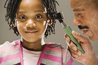 Photo of a young child getting their ears checked by an audiologist